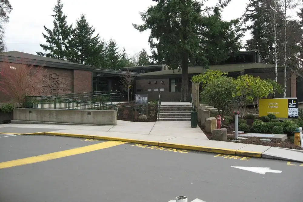 Burien Library building with tall evergreens and a landscaped entrance in Burien, Washington